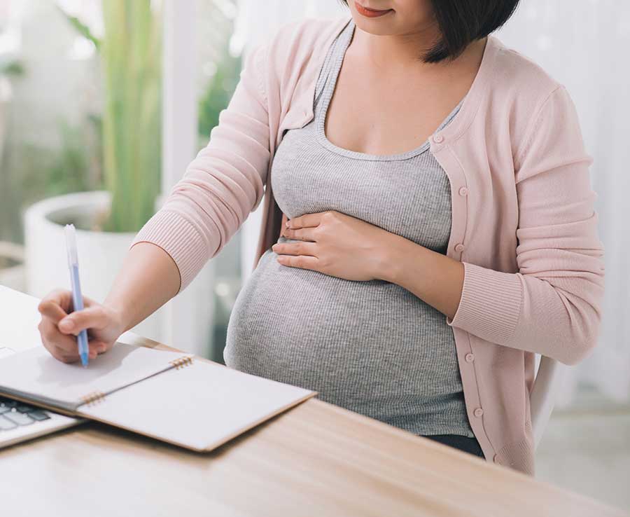 Image d'une femme enceinte assise et prenant des notes